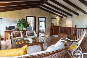 A spacious living area with a chessboard, wicker furniture, and a balcony with a railing. - Beautiful garden, spectacular view and privacy, ideal for nature lovers. (Tegueste)