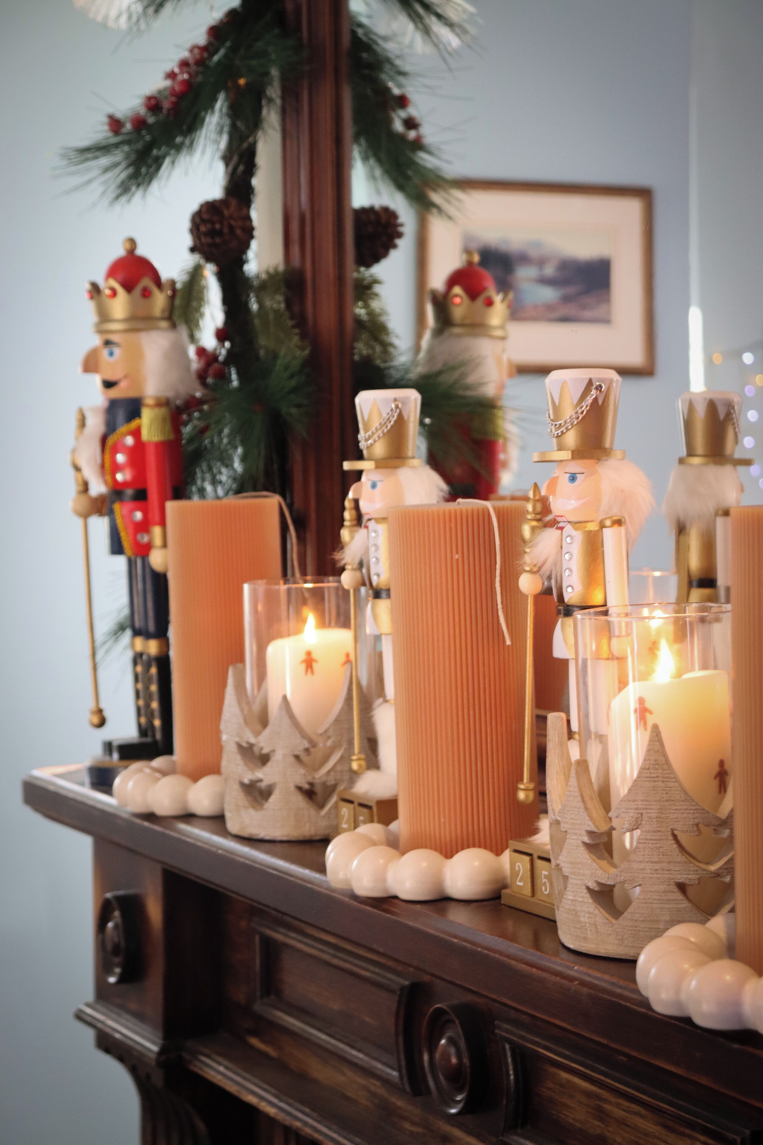A wooden table with candles, nutcracker figurines, and a small Christmas tree.