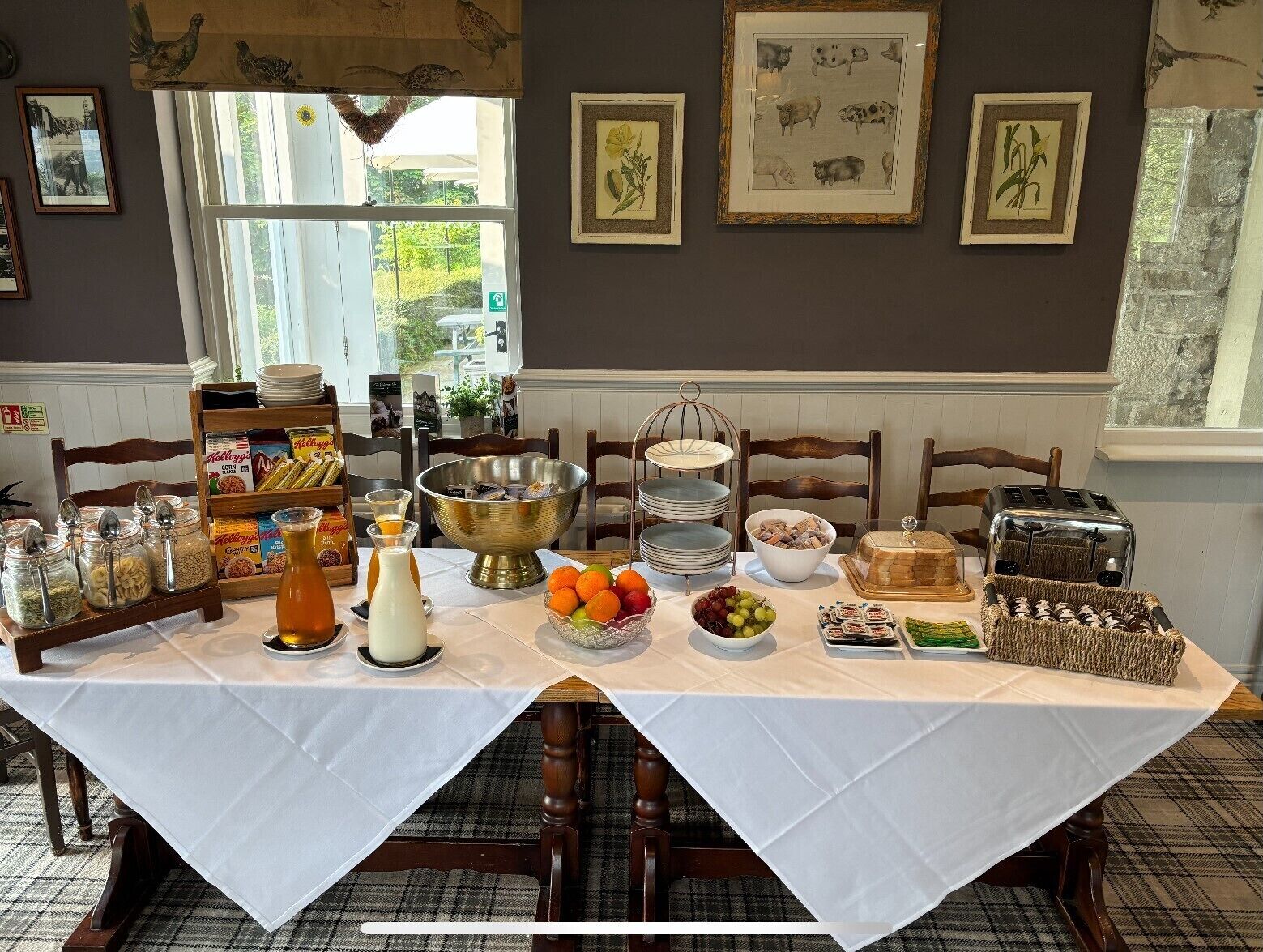 A breakfast buffet setup with various food items and condiments on a table, surrounded by framed pictures on the wall.