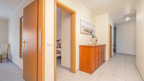 A hallway with wooden doors, a cabinet, and a painting on the wall.