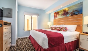 A hotel room with a large bed, a wooden headboard, a painting of palm trees, a window, and a desk with a lamp. - WorldMark Indio - 2 Bedroom/2 Bath Condo for Coachella, sleeps 6 (Indio)
