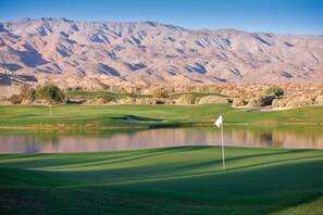 A golf course with a flag, a pond, and mountains in the background. - WorldMark Indio - 2 Bedroom/2 Bath Condo for Coachella, sleeps 6 (Indio)