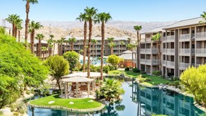 Ein Hotel mit mehreren Etagen, einem Schwimmbad und Palmen.