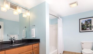 Bathroom features a sink, mirror, toilet, and shower.