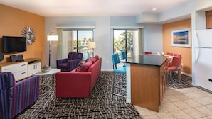 A compact hotel room with a sofa, armchairs, a small dining table, a TV, and a view of the outdoors. - WorldMark Indio, 2 Bedroom/2 Bath Condo for Coachella (Indio)