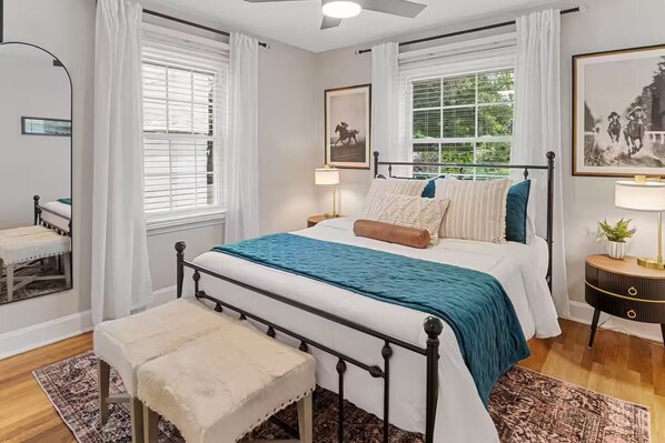 A bedroom with a bed, bedside tables, a bench, and a ceiling fan.