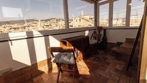 Ein sonnendurchfluteter Balkon mit Blick auf eine Stadtlandschaft, ein Holztisch und zwei Stühle.