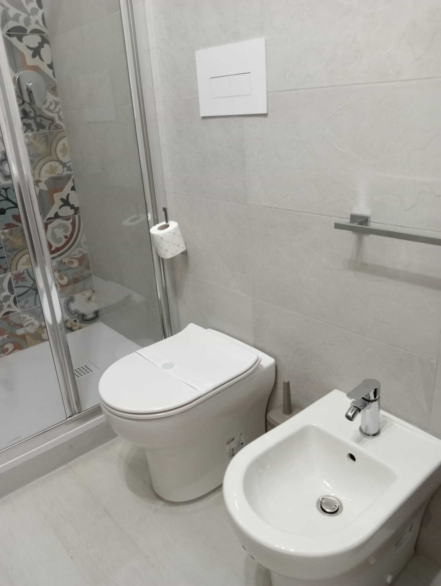 A bathroom with a toilet, bidet, and glass shower enclosure.
