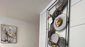 Una sala moderna con un sofá gris, un adorno de pared y una obra de arte enmarcada.