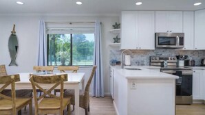 Una cocina moderna con armarios blancos, microondas integrado y una isla grande con pileta.