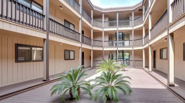 A multi-level atrium with a central open space, surrounded by balconies with railings, and potted plants in the middle.