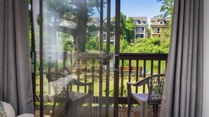 A view through a glass door to a patio with a wooden deck, two chairs, and a table.