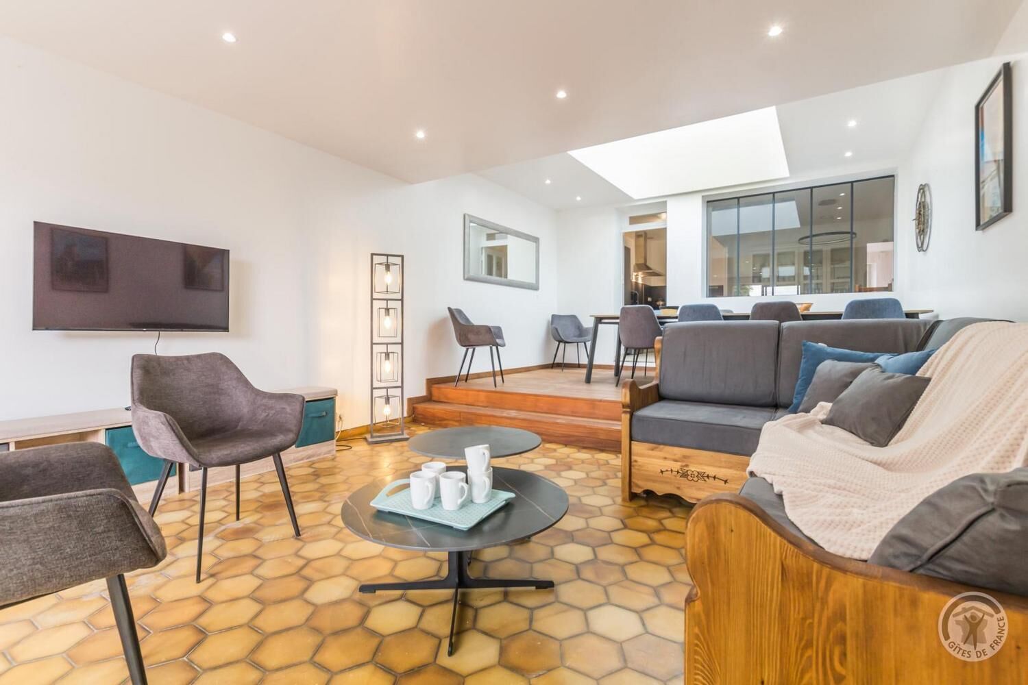 Een moderne woonkamer met een bank, stoelen, een salontafel en een televisie.