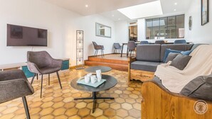 Una sala moderna con sofá, sillones, una mesa de centro y televisor.