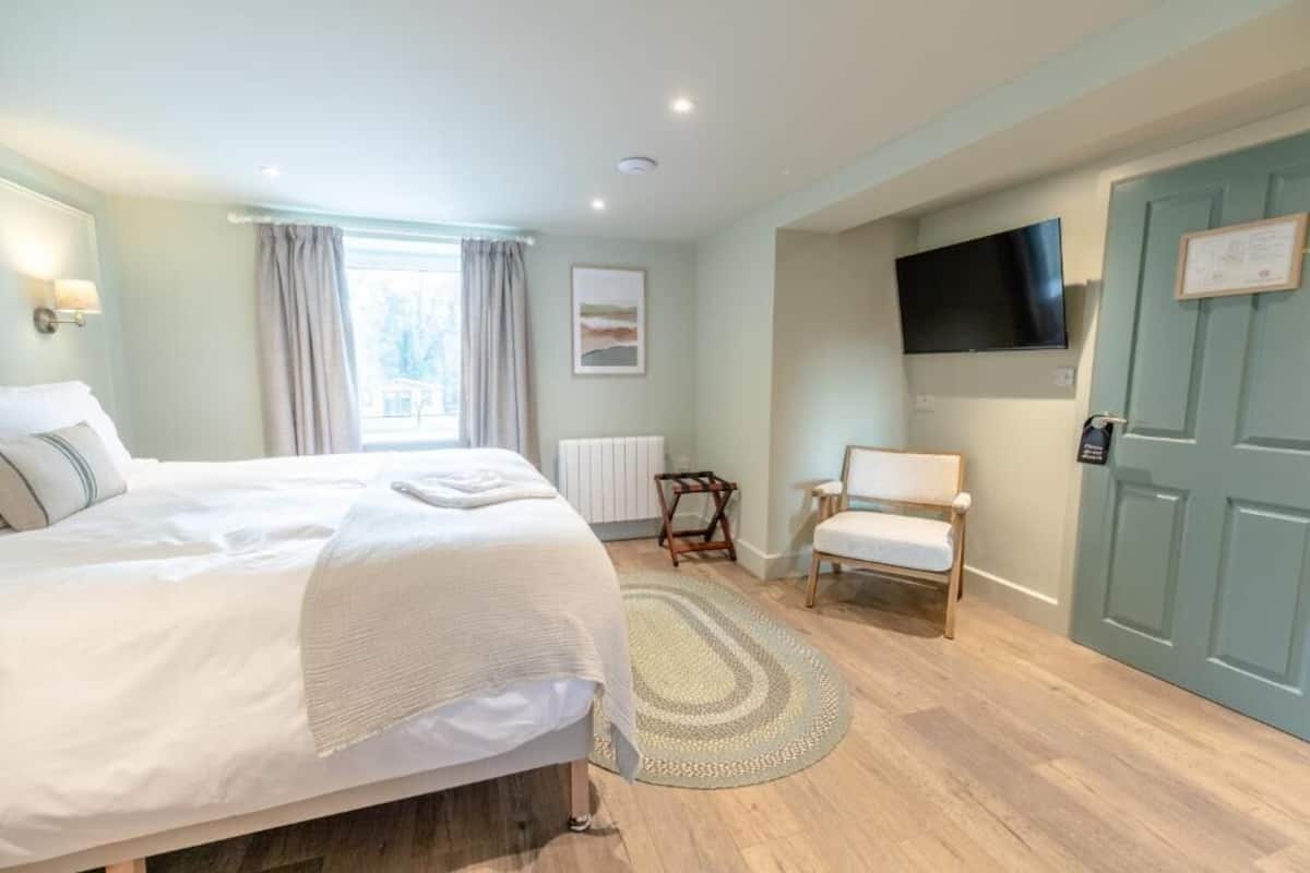A bedroom with a bed, a chair, a TV, and a door.