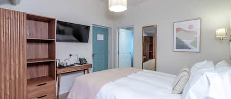 A bedroom with a bed, a desk, a TV, and a wardrobe.