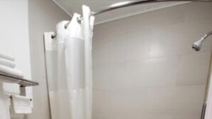 A bathroom with a toilet, a bathtub, and a shower curtain. - Tri-City Motel by OYO Forrest City Spindale (Spindale)