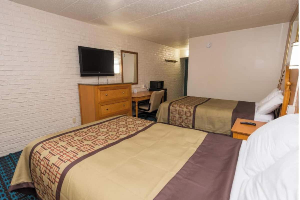 Una habitación de hotel con dos camas, televisión, escritorio y cómoda.