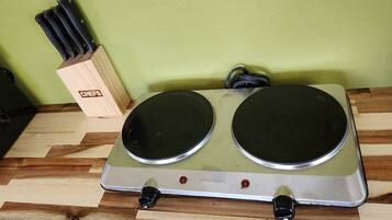 Una cocina con estufa eléctrica doble, un bloque de cuchillos y una pared verde.