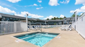 A swimming pool with lounge chairs and a white fence.