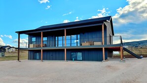 A modern two-story building with large windows, a covered outdoor area, and a staircase leading to the upper level.