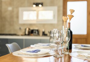 A dining table set with plates, glasses, and a bottle, with a kitchen in the background. -  Apartments Bariloche - San Martin de los Andes Cabins   (San Martín de los Andes)