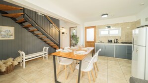 A modern kitchen with a wooden table and chairs, a built-in stove, and a refrigerator. -  Apartments Bariloche - San Martin de los Andes Cabins   (San Martín de los Andes)