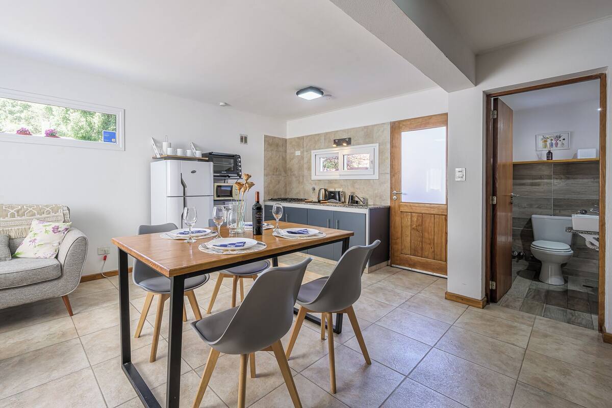 Un espace de vie compact comprenant un coin repas, une kitchenette et une petite salle de bain.