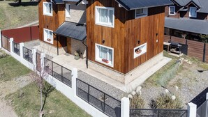 A two-story wooden house with a fenced yard and a small garden area. -  Apartments Bariloche - San Martin de los Andes Cabins   (San Martín de los Andes)