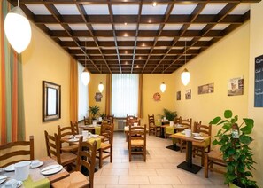 A cozy cafe with wooden tables and chairs, a tiled floor, and a ceiling with exposed beams. - Hotel Schwert (Kehl)