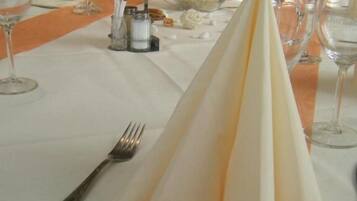 A long dining table set with multiple wine glasses, a candle, and a salt and pepper shaker.