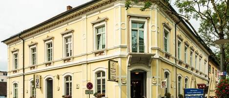 Ein historisches Hotel mit einer klassischen Fassade, einem zentralen Eingang und einem Schild, das es als Hotel kennzeichnet.