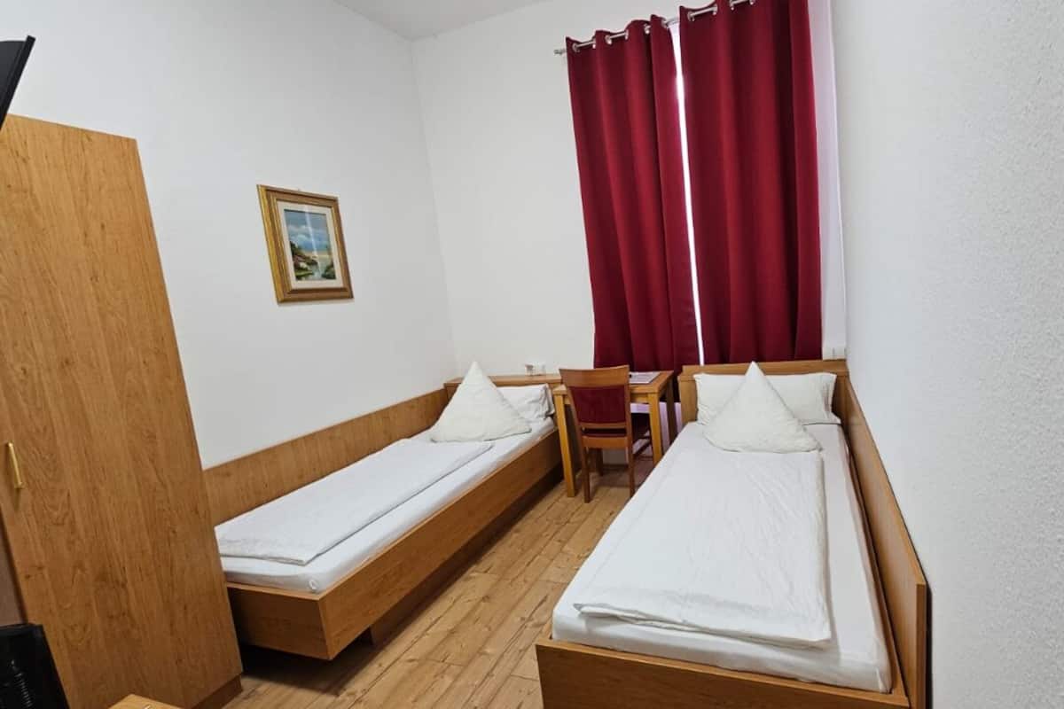 A small room with two wooden beds, a desk, and a chair.