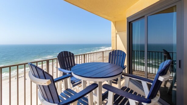 Un balcon avec une table et des chaises donnant sur l’océan.
