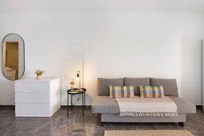 A modern room with a sofa, a side table with a lamp, a mirror, and a white dresser.