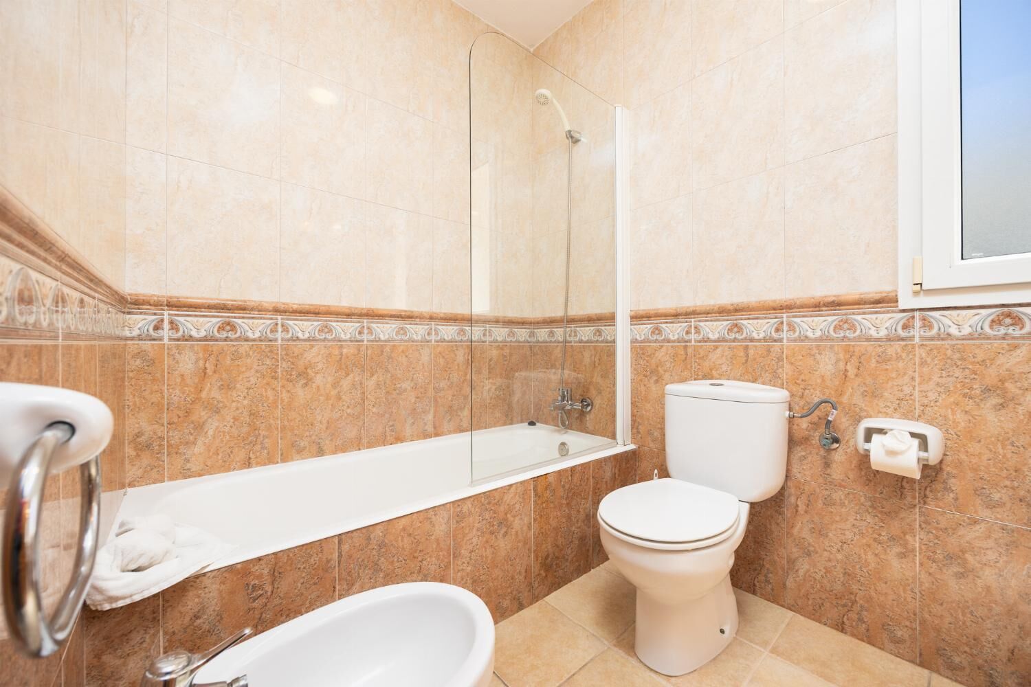 Een badkamer met een bad, toilet en douche.