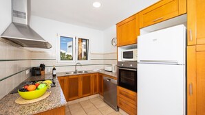 Une cuisine moderne avec des meubles en bois, une hotte en acier inoxydable, un four encastré, un four à micro-ondes et un plan de travail en granit.