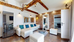 Un salon moderne avec un canapé blanc, une table basse en verre et un mur décoratif en briques.