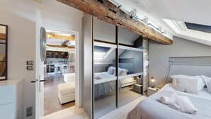 Une chambre à coucher moderne avec un lit de style industriel, un puits de lumière et une cuisine ouverte.
