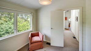 Ein Zimmer mit großem Fenster, einer Tür zu einem anderen Raum und einem Sessel.