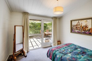 Een slaapkamer met een bed, een groot raam, een schilderij en een houten vloer.