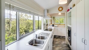 Eine moderne Küche mit großem Fenster, eingebautem Ofen und weißen Schränken.