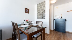 Un comedor con una mesa de vidrio, sillas de madera y una ventana con vidrios decorativos.