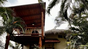 Ein tropisches Resort mit einer Holzpergola, einem Gebäude mit Strohdach und üppigen Palmen.