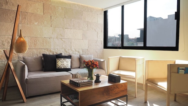 A modern living room with a stone wall, a wooden coffee table, a sofa, and a chair. - Mirador Pushkin by The Local Way (Mexico City)