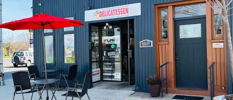 A building with a sign reading 'DELICATESSEN' and a red umbrella outside.