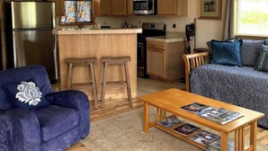 Un espace de vie compact comprenant un coin cuisine, un canapé, une table basse et une fenêtre avec vue.