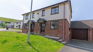 A two-story building with a brick facade, a front entrance with a door, and a small porch area. - Cockleshell Croyde | Sleeps 4 | By the Seaside (Croyde)