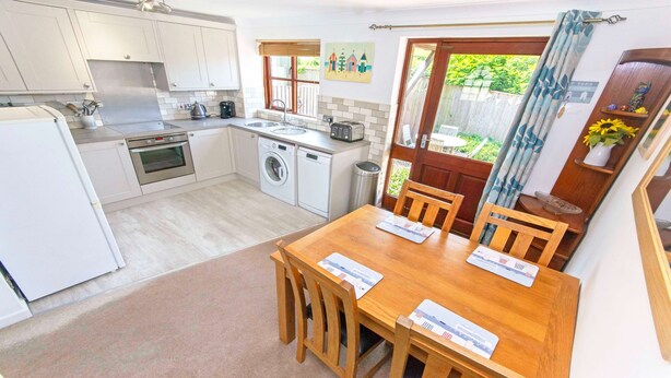 A compact kitchen with a washing machine, a coffee maker, and a toaster. - Cockleshell Croyde | Sleeps 4 | By the Seaside (Croyde)