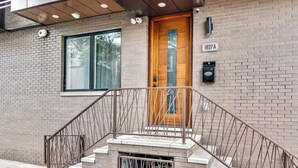 Un edificio de dos pisos con fachada de ladrillo, puerta principal de madera y escalera de metal.